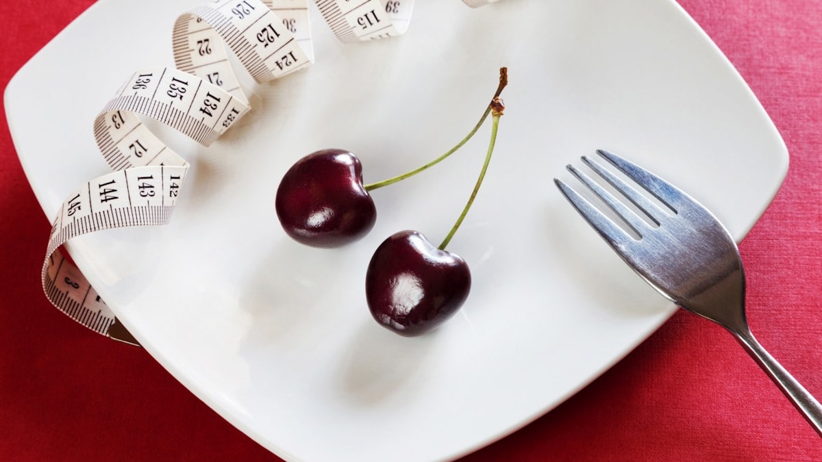 Diet white plate with centimeter, cherry, fork