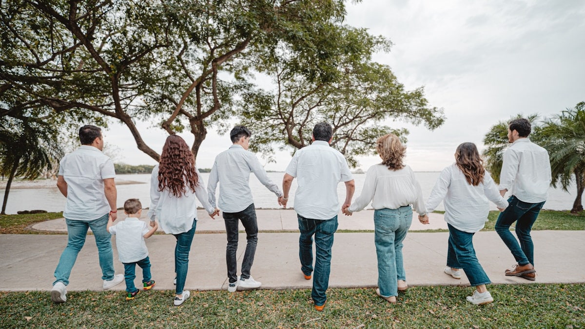 Family holding hands walking by the water